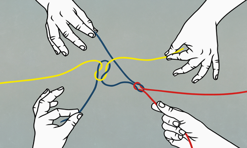 Two pairs of hands tying coloured string
